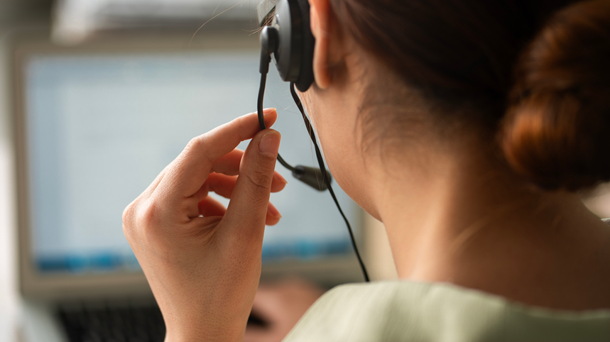 Woman on headset phone looking at a computer