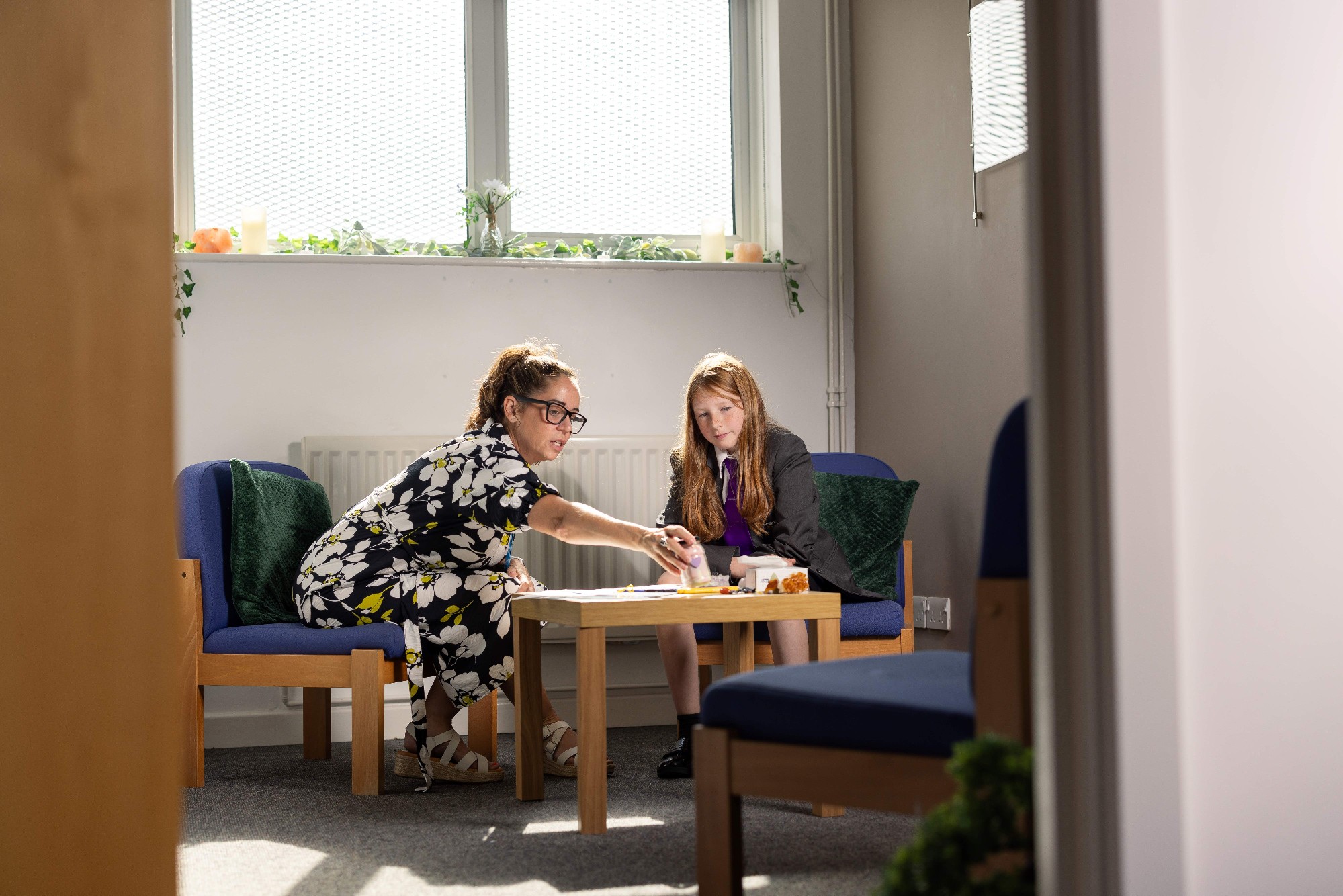 A clinician and a young girl focusing on an activity on a table.jpg