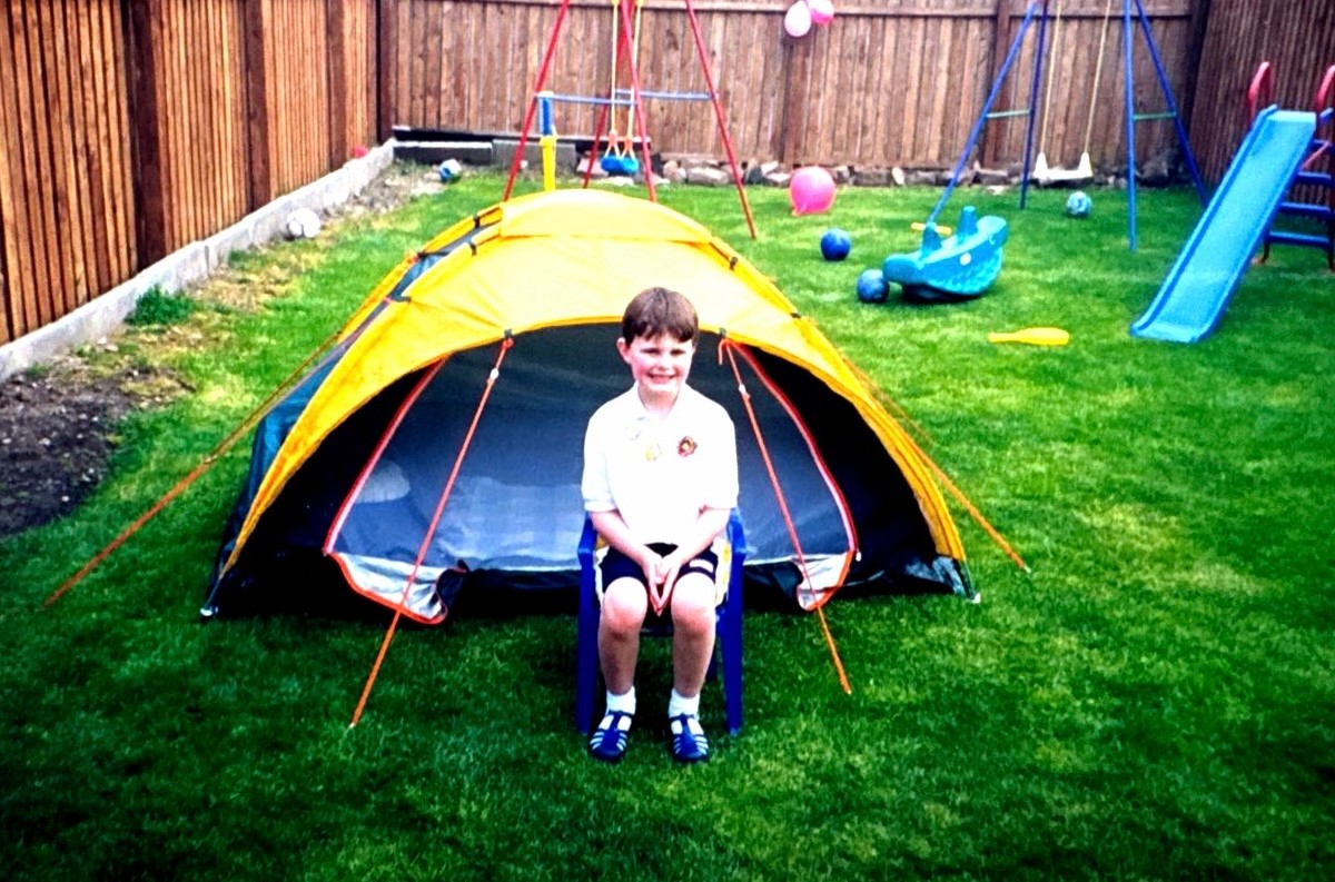 A young Scott sitting proudly outside his garden tent. A mini out house to escape to. .jpg