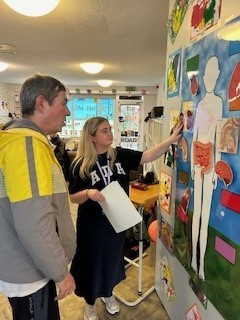 A man and woman looking at a model of the human body, as part of a cancer information session.jpg